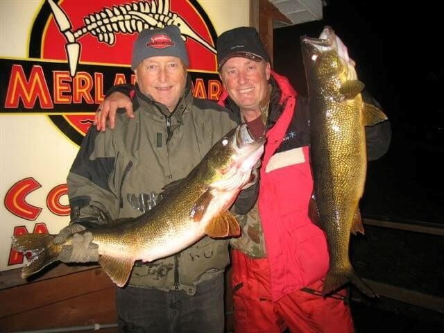 Two smiling fisherman hold the fish they caught.