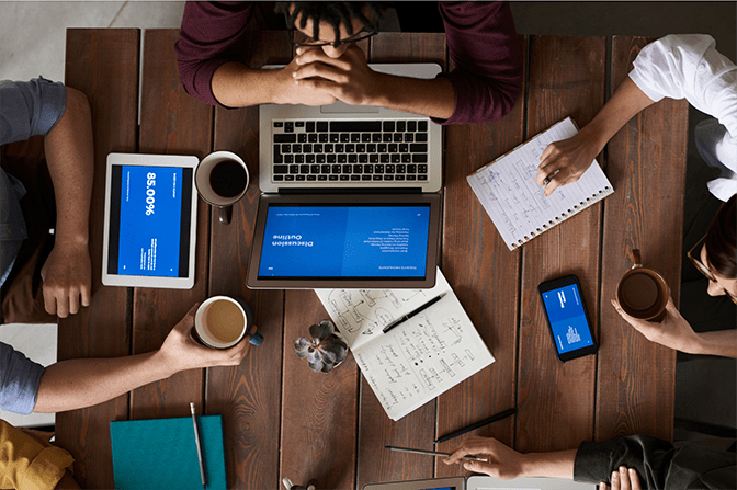 Ceiling view of 4 people sitting around a table having a business meeting with coffee, laptops and notebooks
